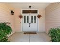 Close-up of the double front doors, enhanced by hanging flower baskets and a welcoming pineapple doormat at 712 Harper Pl, Lady Lake, FL 32159