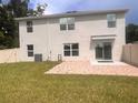 View of the back exterior featuring a brick patio, sliding glass doors, and a spacious grassy yard at 11136 Se 69Th Ter, Belleview, FL 34420