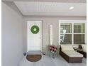 Inviting front porch with a 'Welcome' sign, decorative wreath, seating, and lush greenery at 13164 Sw 78Th Place, Dunnellon, FL 34432