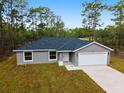 Inviting single-story home showcasing a gray exterior, attached garage, concrete driveway and naturally landscaped front yard at 24354 Nw Water Oak Ave, Dunnellon, FL 34431