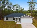Inviting single-story home showcasing a gray exterior, attached garage, concrete driveway and naturally landscaped front yard at 24354 Nw Water Oak Ave, Dunnellon, FL 34431