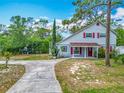 Charming blue two-story home with a covered front porch, red door, and mature landscaping at 6403 Summit Dr, Orlando, FL 32810