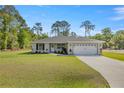Single-story home boasts a manicured front lawn, a long driveway, and an attached two-car garage at 77 Locust Dr, Ocala, FL 34472