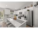 Bright kitchen features white cabinets, stainless steel appliances, and an island with seating at 77 Locust Dr, Ocala, FL 34472