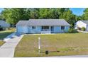 Inviting single-story home with a tidy front lawn, attached garage, and a quaint front porch at 9058 Sw 108Th Pl, Ocala, FL 34481