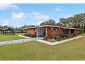 Red brick home with a covered carport, neatly manicured landscaping, a gazebo and a lush green lawn at 9900 Ne 20 Terrace Rd, Anthony, FL 32617