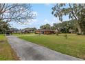 Expansive front yard with a red brick home, carport, gazebo, and a long driveway lined with trees at 9900 Ne 20 Terrace Rd, Anthony, FL 32617