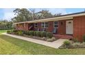 Inviting red brick home featuring a cozy porch with blue Adirondack chairs and well-manicured landscaping at 9900 Ne 20 Terrace Rd, Anthony, FL 32617