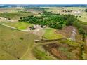 Sprawling land featuring a residence, barn, and green pastures, complemented by a nearby wooded area and distant fields at 22111 Obrien Rd, Howey In The Hills, FL 34737