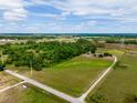 Scenic aerial view showcasing the property's vast green spaces, a long driveway, surrounding woodlands, and a peaceful, rural setting at 22111 Obrien Rd, Howey In The Hills, FL 34737