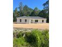 An exterior of new construction with white siding and a gray roof, surrounded by lush greenery at 3 Redwood Track Run, Ocala, FL 34472