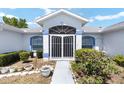 Close-up view of a white and blue home's front entrance, featuring a secure gated door and lush landscaping at 4085 Sw 110Th St, Ocala, FL 34476
