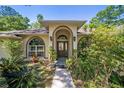 Charming front entrance featuring an arched entryway, tropical landscaping, and updated lighting at 6150 Nw 59Th Ave, Ocala, FL 34482