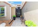 Inviting front porch area with a decorative wall hanging, bench, potted plants, and a brick walkway at 7167 Sw 99Th Cir, Ocala, FL 34481