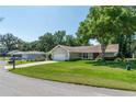 A single-story home with an attached two-car garage, a well-manicured lawn and mature trees at 8120 Nw 48Th Ln, Ocala, FL 34482
