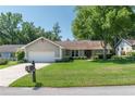 Traditional single-story home featuring an attached two-car garage, landscaped yard, and mature trees at 8120 Nw 48Th Ln, Ocala, FL 34482