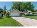 Two car attached garage in a single-story home featuring a well-manicured lawn and mature trees at 8120 Nw 48Th Ln, Ocala, FL 34482