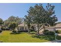 Well-maintained single-story home featuring lush front lawn with mature trees and an attached two-car garage at 9325 Se 132Nd Pl, Summerfield, FL 34491