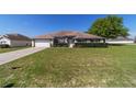 Charming single-story home with manicured lawn, mature landscaping, and an attached two-car garage at 9896 Sw 56Th Ct, Ocala, FL 34476