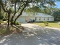Spacious home with a paved driveway leading to an attached garage, surrounded by mature trees at 9915 Sw 47Th Ave, Ocala, FL 34476