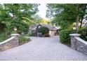 Long driveway with stone pillars leading to a well-maintained home surrounded by lush trees at 1450 Se 73Rd Pl, Ocala, FL 34480