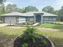 Charming single-story home with a beautifully landscaped front yard and a blue front door at 20364 Sw 86Th Loop, Dunnellon, FL 34431