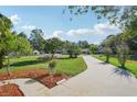 Scenic view of a long driveway leading to a well-maintained home with lush landscaping and a blue sky backdrop at 28 Gordon Ct, Leesburg, FL 34788