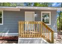 Close up of new wooden staircase leading to the front door of the home with gray wood siding at 6840 Sw 198Th Ave, Dunnellon, FL 34431