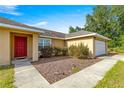 Welcoming front entrance with tidy landscaping, a vibrant red door, and a two car garage at 8 Hemlock Radl, Ocala, FL 34472