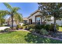 Well-manicured front yard with landscaped garden beds and a charming home exterior with a red front door at 9443 Sw 71St Loop, Ocala, FL 34481