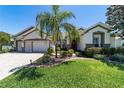 Inviting home exterior featuring lush green lawn, a palm tree, and a brick driveway leading to a two-car garage at 9443 Sw 71St Loop, Ocala, FL 34481