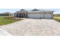 Paver driveway leads to a three-car garage enhancing the curb appeal of this modern home at 9973 Sw 107Th Ter, Ocala, FL 34481