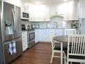 Bright kitchen features white cabinets, stainless steel appliances, and a cozy dining area at 12002 Sw 137Th Loop, Dunnellon, FL 34432