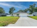 Inviting single-story home with a well-kept lawn, an attached garage, and a mix of stone and siding accents at 13588 Se 102Nd Ct, Belleview, FL 34420
