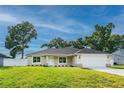 Single-story home with a manicured lawn, an attached garage, and a combination of stone and siding accents at 13588 Se 102Nd Ct, Belleview, FL 34420