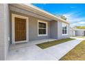 Inviting covered front porch featuring a stylish wood front door, modern paint, and freshly poured concrete at 37 Fisher Lane Way, Ocklawaha, FL 32179
