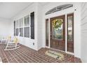 Cozy front porch with brick flooring, rocking chairs, a decorative wreath, and a welcoming 
