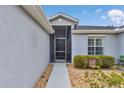 Close up of the screened entrance with gray siding, a front door, and manicured landscaping at 15239 Sw 15Th Terrace Rd, Ocala, FL 34473
