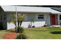 Landscaped front yard with a charming red door and freshly painted light gray exterior at 2219 Ne 18 Ave, Ocala, FL 34470