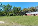 Large green lawn leading to a rustic red barn with abundant trees and a clear blue sky in the background at 2630 Nw 140Th St, Citra, FL 32113