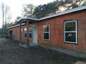 The side view of the single-story home featuring an entrance porch, a metal roof and several windows at 2630 Nw 140Th St, Citra, FL 32113