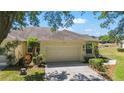 Attached two-car garage with a concrete driveway and mature landscaping at 9591 Sw 70Th Loop, Ocala, FL 34481