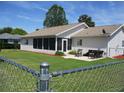 Spacious backyard featuring a screened-in porch, patio area with furniture, and chain-link fence at 11536 Sw 138Th Ln, Dunnellon, FL 34432