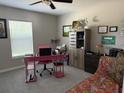 Cozy bedroom with a ceiling fan, large window with blinds, and a fun pink desk and chair at 13356 Sw 66Th St, Ocala, FL 34481