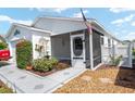 Charming home featuring a landscaped yard, an American flag, and a cozy screened-in porch at 2693 Craven Way, The Villages, FL 32162