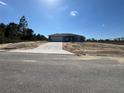 A single-story home with a gray exterior, concrete driveway, a front yard covered with sand, and a blue sky at 4424 Sw Carnation Ct, Dunnellon, FL 34431