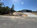 A single-story home with a gray exterior, concrete driveway, a front yard covered with sand, and a blue sky at 4424 Sw Carnation Ct, Dunnellon, FL 34431