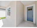 View of a charming home entrance featuring a blue front door and adjacent window with white trim at 4778 Se 25Th Loop, Ocala, FL 34480