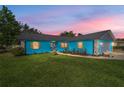 Twilight view of an inviting single-story home with vibrant blue exterior and manicured lawn at 5220 Sw 161St Place Rd, Ocala, FL 34473