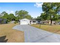 Single-story home with a gray driveway leading to an attached garage, nestled in a serene neighborhood at 614 Third Ave, Lady Lake, FL 32159